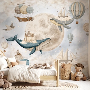 Op de afbeelding: Een muurschildering met een grote beige maan, blauwe walvissen die kastelen dragen, heteluchtballonnen en zeilschepen in een bewolkte lucht. De scène bevat een houten bed met wit beddengoed, een rond kleed en twee gevlochten manden.