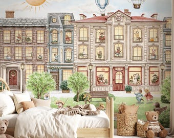 May include: Watercolor mural depicting a whimsical town scene with buildings, trees, and hot air balloons. The buildings have windows with animal characters. A wooden bed, rug, and teddy bears are in the foreground.