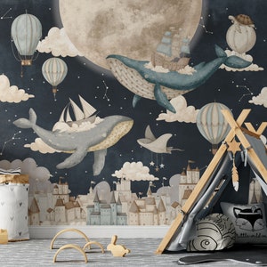 May include: A whimsical nursery wall mural featuring a dark blue night sky with a large, full moon, clouds, stars, and a city skyline.  Two blue whales are flying through the sky, one carrying a ship and the other carrying a sailboat.  There are also hot air balloons and a small, gray flying creature.