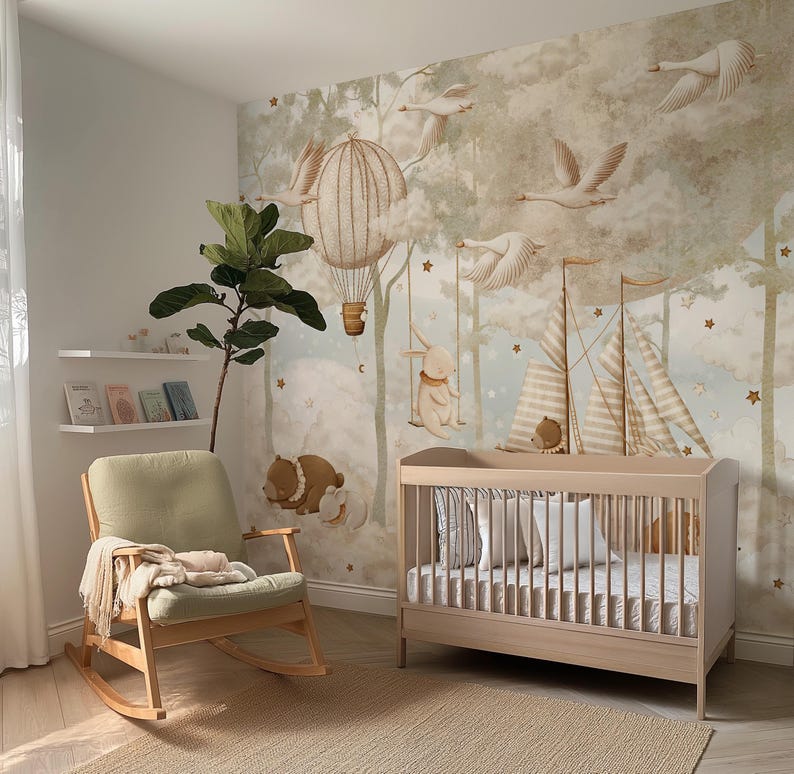 Op de afbeelding: Een kinderkamer met een licht houten wieg, een schommelstoel en een grillige muurschildering met luchtballonnen, zwanen en bosdieren. De kamer heeft een neutraal kleurenpalet met een beige tapijt en een groene plant.