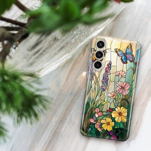 May include: A clear phone case featuring a stained-glass design with butterflies, flowers, and foliage in shades of yellow, pink, blue, and purple. The case has a glossy finish and a camera cutout.