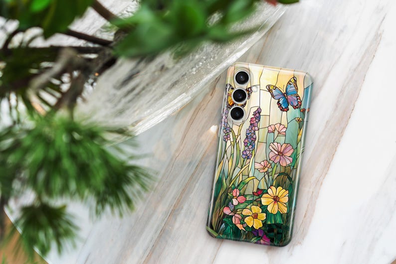 May include: A clear phone case featuring a stained-glass design with butterflies, flowers, and foliage in shades of yellow, pink, blue, and purple. The case has a glossy finish and a camera cutout.