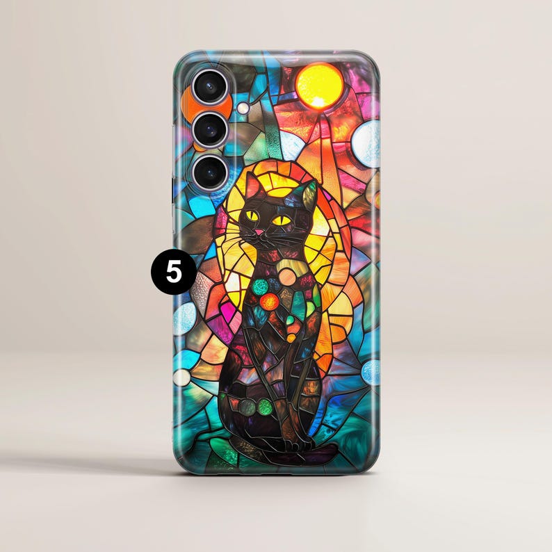 May include: A black cat with yellow eyes sits in a stained glass design phone case. The case has a colorful design with a sun and planets. The case is for a phone with a triple camera lens.