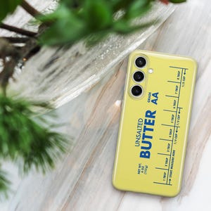 May include: A yellow phone case with a stick of butter design. The case has a blue label that reads "Unsalted Butter AA Grade" and a measurement guide in tablespoons and cups.