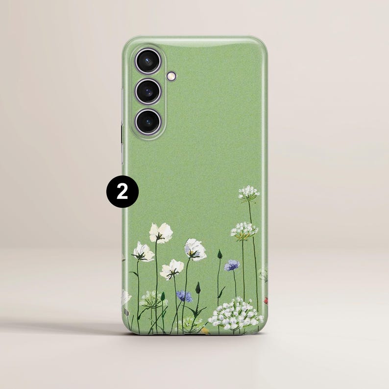 May include: A light green phone case with a floral design. The case features a field of white, purple, and green flowers along the bottom edge. The number "2" is printed in black on the upper left corner.