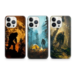 May include: Three different iPhone cases with a Bigfoot theme. The first case features a silhouette of Bigfoot walking in front of a full moon. The second case shows Bigfoot standing in a forest with a tent and campfire. The third case shows Bigfoot walking through a forest.