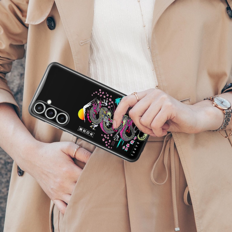 Pu&ograve; includere: Una custodia per telefono nera con un design di drago colorato e testo giapponese. La custodia ha un rialzo della fotocamera rialzato con tre obiettivi.