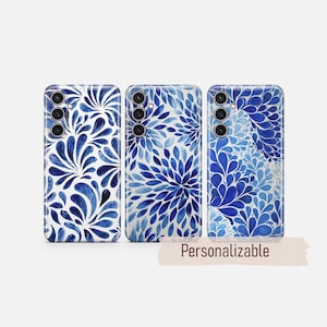 Könnte beinhalten: Drei Handyhüllen mit blauen Blumenmustern. Die Hüllen zeigen verschiedene blaue Designs im Aquarellstil, darunter stilisierte Blätter und blütenartige Anordnungen. Das Wort "Personalisierbar" ist auf einem Banner darunter gedruckt.