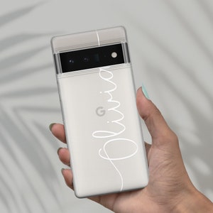 Op de afbeelding: Een witte telefoonhoes met een transparante achterkant en een zwarte camera lens. De hoes heeft de naam "Olivia" in wit cursief op de achterkant.