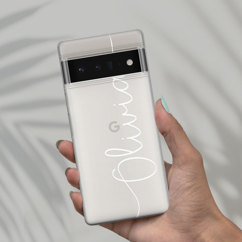 Op de afbeelding: Een witte telefoonhoes met een transparante achterkant en een zwarte camera lens. De hoes heeft de naam "Olivia" in wit cursief op de achterkant.