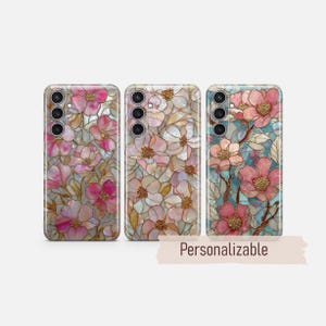 May include: Three phone cases with floral designs. The cases feature pink and gold flowers with a stained glass effect. The text "Personalizable" is displayed on a banner below the cases.