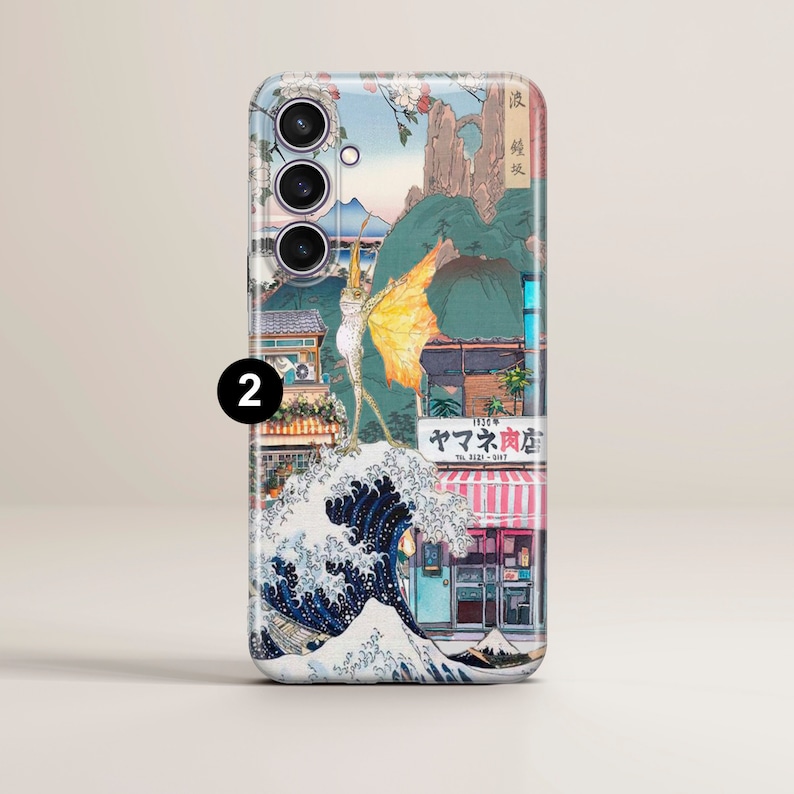 Op de afbeelding: Een telefoonhoesje met een kleurrijk Japans ge&iuml;nspireerd ontwerp met een golf, een gebouw met de tekst "ヤマト肉店" en een vliegende creatuur. Het hoesje heeft een transparante achterkant en een zwarte camera-uitstulping met drie lenzen.