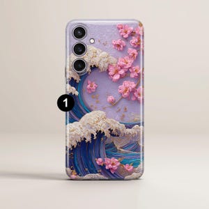 May include: A phone case featuring a Japanese-inspired design. The case showcases a wave pattern in shades of blue and white, with pink cherry blossoms. The phone case has a camera module with three lenses.