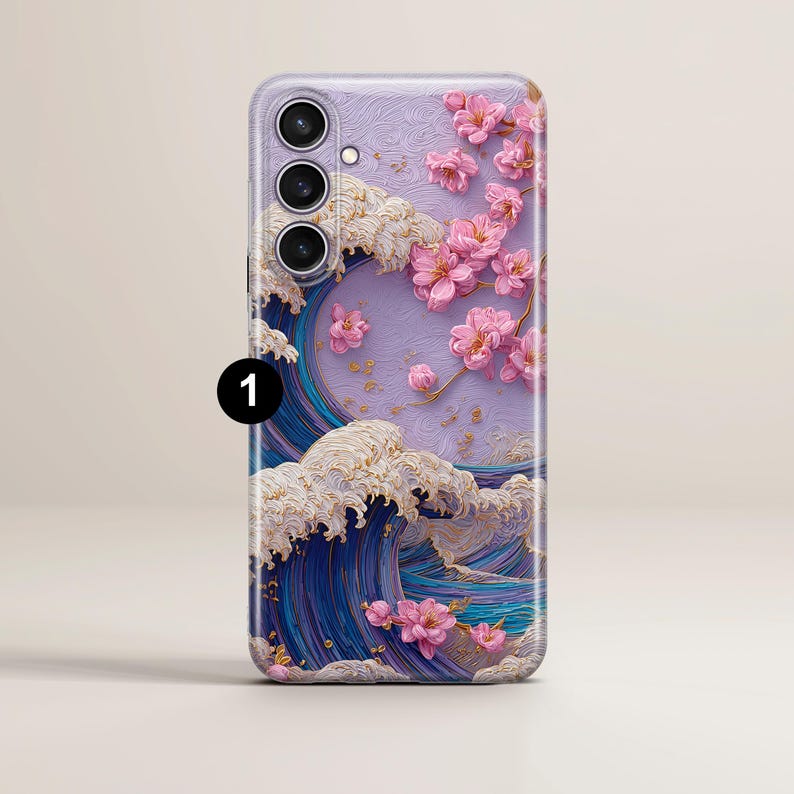 May include: A phone case featuring a Japanese-inspired design. The case showcases a wave pattern in shades of blue and white, with pink cherry blossoms. The phone case has a camera module with three lenses.