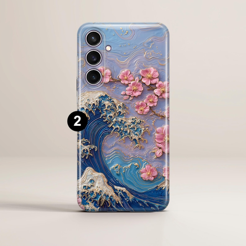 May include: A phone case featuring a 3D design of a Japanese wave with gold accents and pink cherry blossoms. The case has a blue and purple background with a textured appearance, and a camera cutout.
