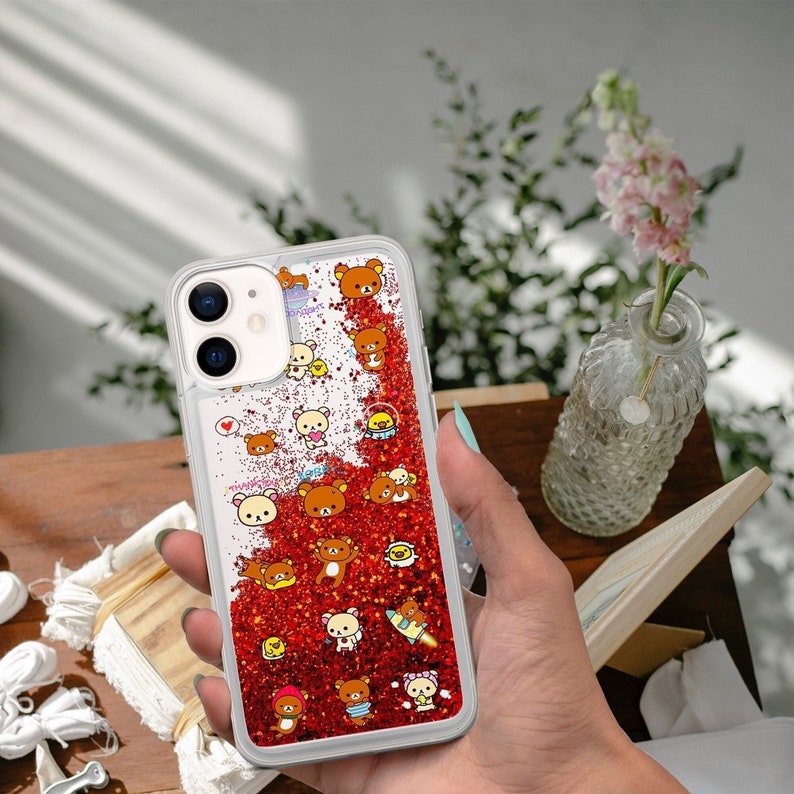 May include: A clear phone case with a red glitter background and a pattern of brown bears. The case has a cutout for the camera lens and a clear border.
