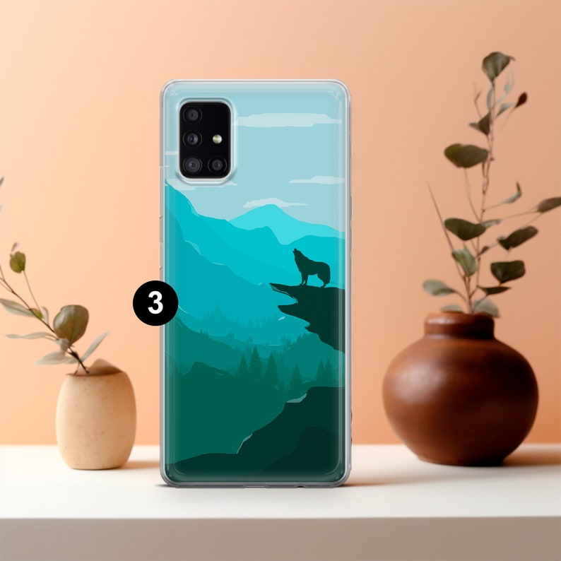 May include: A clear phone case with a wolf silhouette howling at the moon over a mountain range. The mountains are a gradient of blue and green.