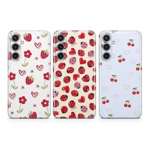 Può includere: Tre custodie per telefono con design diversi. La prima custodia ha uno sfondo bianco con fragole rosse, cuori e fiori. La seconda custodia ha uno sfondo bianco con coccinelle rosse e cuori. La terza custodia ha uno sfondo blu chiaro con ciliegie rosse e cuori.