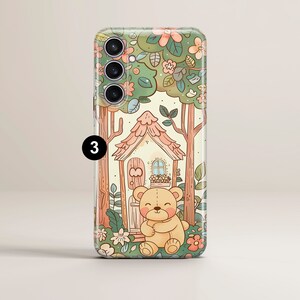May include: A phone case with a cute cartoon illustration of a teddy bear sitting in front of a small house in a forest. The house has a pink roof and a brown door. The forest is filled with green trees and pink flowers.