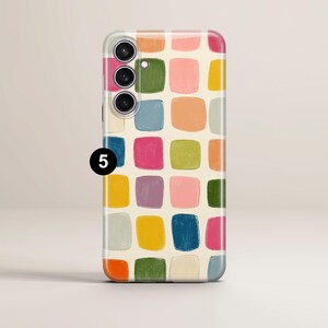 May include: A smartphone case with a colorful, abstract pattern of squares in shades of pink, green, blue, orange, and yellow. The case has a cream-colored background and a camera module with three lenses.