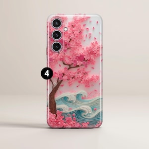 May include: A phone case featuring a pink cherry blossom tree with falling petals and blue and white waves. The case has a glossy finish and a detailed, textured design. The phone case has three camera lenses.