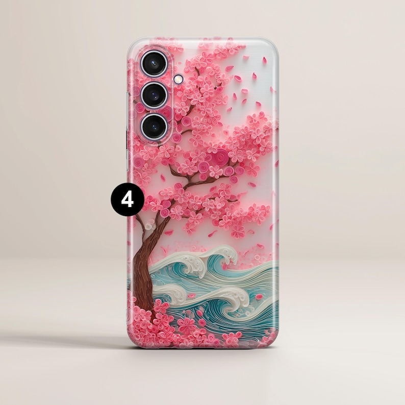 May include: A phone case featuring a pink cherry blossom tree with falling petals and blue and white waves. The case has a glossy finish and a detailed, textured design. The phone case has three camera lenses.