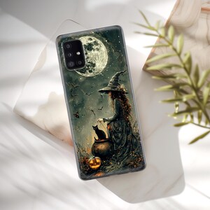 May include: A phone case with a witch and a black cat in front of a full moon. The witch is wearing a black hat and dress. The cat is sitting on a cauldron. There is a pumpkin in the foreground.