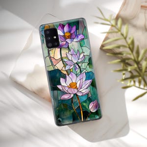 Op de afbeelding: Een telefoonhoesje met een glas-in-loodontwerp met drie paarse en witte lotusbloemen op een groene achtergrond.