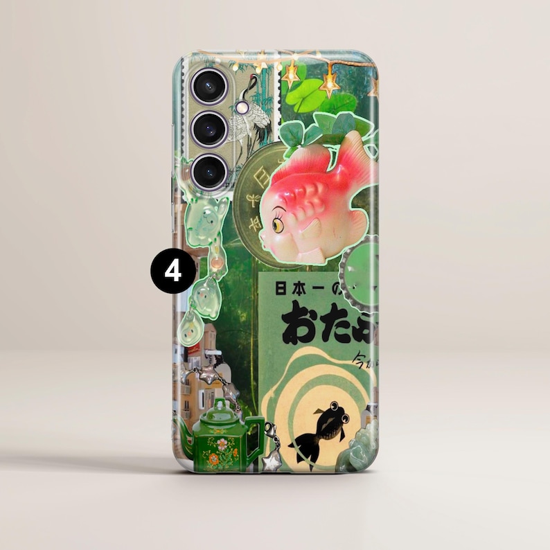 May include: A green and white phone case with a collage of images, including a red fish, a teapot, and Japanese text. The text reads "日本一の おたまで"