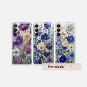 May include: Three phone cases with floral designs. The cases feature a variety of flowers in shades of purple, blue, white, and yellow. The cases have a glossy finish and the text "Personalizable" is visible.