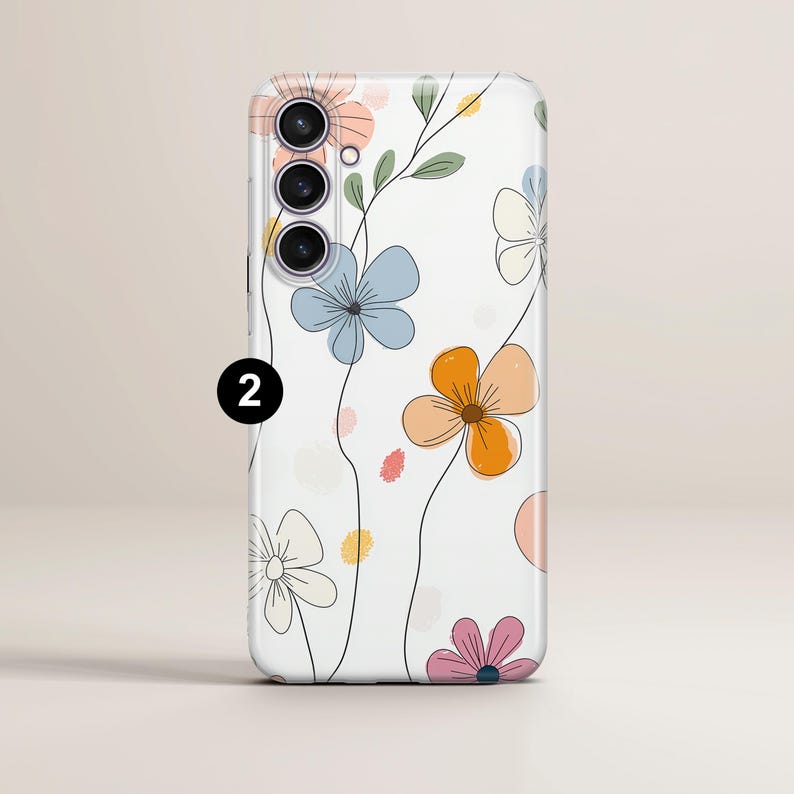 May include: A white phone case featuring a floral design with pastel-colored flowers and green leaves. The flowers are in shades of orange, blue, pink, and peach, with black line art. The phone case has a camera module with three lenses.