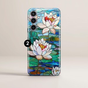 Op de afbeelding: Een telefoonhoesje met een glas-in-loodontwerp met witte waterlelies op een blauwe en groene achtergrond. Het hoesje heeft een camera-uitsparing met drie lenzen.