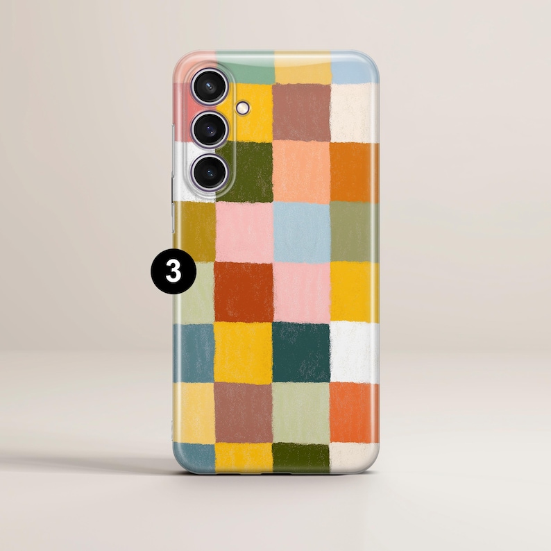 May include: A smartphone case with a colorful, abstract checkerboard pattern. The design features squares of various colors, including pink, yellow, green, and brown. The case has a camera module with three lenses and a flash.