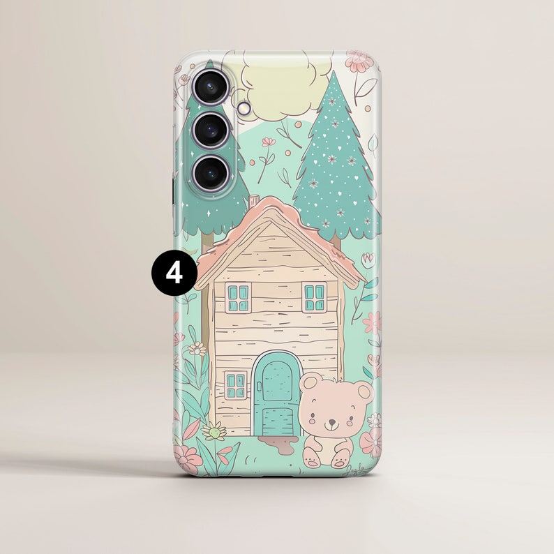 May include: A clear phone case with a cute cartoon design featuring a small wooden house, two trees, and a teddy bear. The house has a blue door and windows. The trees are green with white dots. The background is a light blue with pink flowers.
