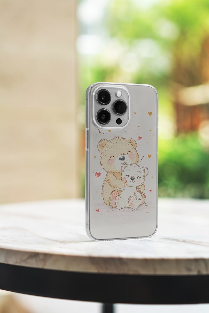 May include: A clear phone case with a cute illustration of two teddy bears hugging. The bears are surrounded by small pink hearts. The case is designed for an iPhone.