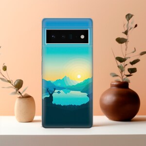 May include: A clear phone case with a scenic landscape design. The image features a mountain range, a lake, a deer, and a sunset. The case is designed for a phone with a triple camera system.