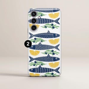May include: A white phone case with a repeating pattern of navy blue fish, yellow lemon slices, and olive branches. The design has a nautical theme. The phone case has a camera cutout with three lenses.