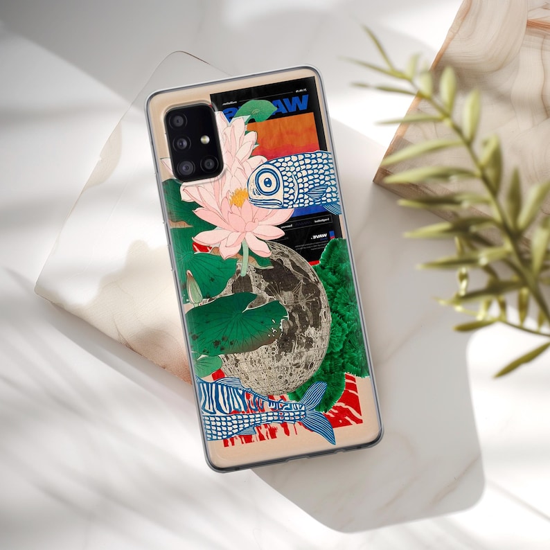 May include: A phone case with a colorful design featuring a lotus flower, fish, and a moon. The design is in a Japanese style.