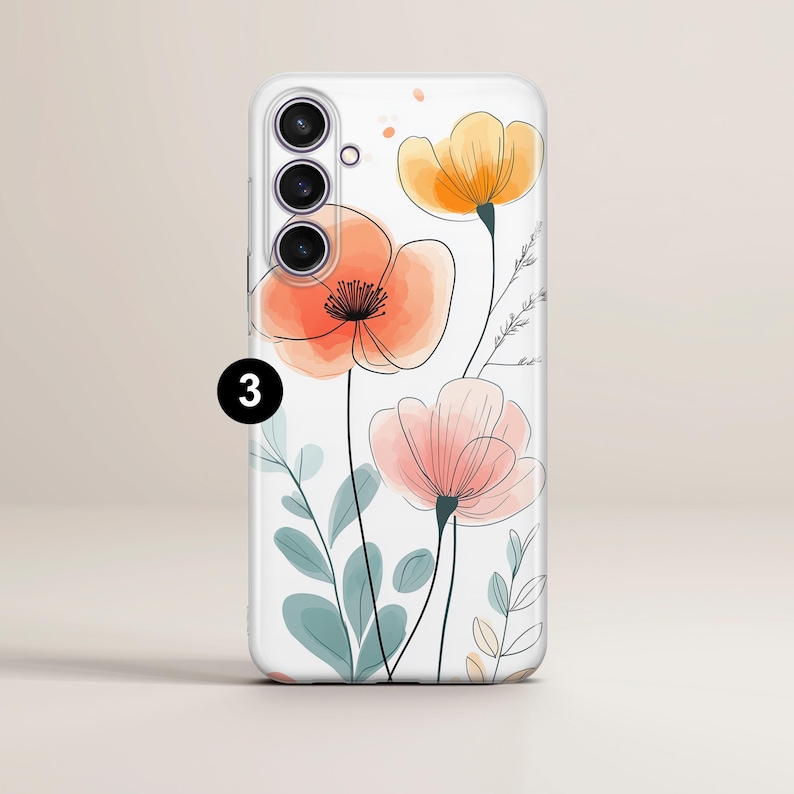 May include: A white phone case featuring a watercolor floral design. The case has a clear background with orange, peach, and yellow flowers, along with green and blue leaves. The phone case has a triple-lens camera.