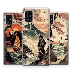 Pode incluir: Três capas para telemóvel com um design de inspiração japonesa. A capa do centro apresenta uma montanha, uma cachoeira, uma pessoa com roupas tradicionais e um barco na água. A capa da esquerda apresenta uma montanha, um barco e um sol vermelho. A capa da direita apresenta uma montanha, um barco e uma cerejeira em flor.