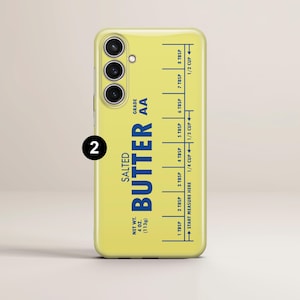 May include: A yellow phone case with a blue and white butter stick label. The label says "Salted Butter AA" and has a measurement guide in tablespoons and cups. The case has a 2 printed on the side.