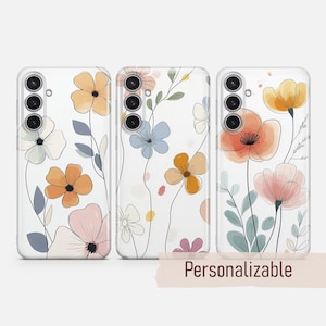 May include: Three clear phone cases with floral designs. Each case features a different arrangement of watercolor-style flowers in shades of orange, pink, blue, and yellow, with green leaves and stems. The cases have a black camera array. The word "Personalizable" is at the bottom.