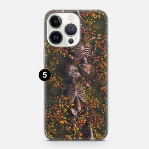 May include: A clear phone case with a design of two skeletons lying in a field of yellow and red flowers. The skeletons are intertwined and appear to be embracing.