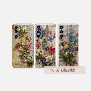 Puede incluir: Tres fundas para teléfono con diseños florales. Cada funda presenta una disposición diferente de flores secas en varios colores, sobre un fondo de papel envejecido con texto manuscrito. Las fundas están etiquetadas como "Personalizable".