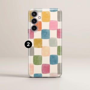 May include: A phone case with a colorful, abstract design. The case features a pattern of irregular squares in various pastel colors, including yellow, orange, blue, pink, and green, set against a cream background. The phone's camera lenses are visible.
