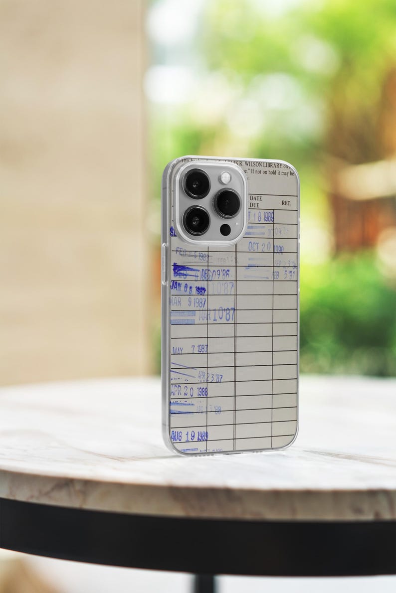 May include: A clear phone case with a library card design. The case has a date due section with handwritten dates from 1986 to 1989. The text "WILSON LIBRARY" is visible at the top of the case.