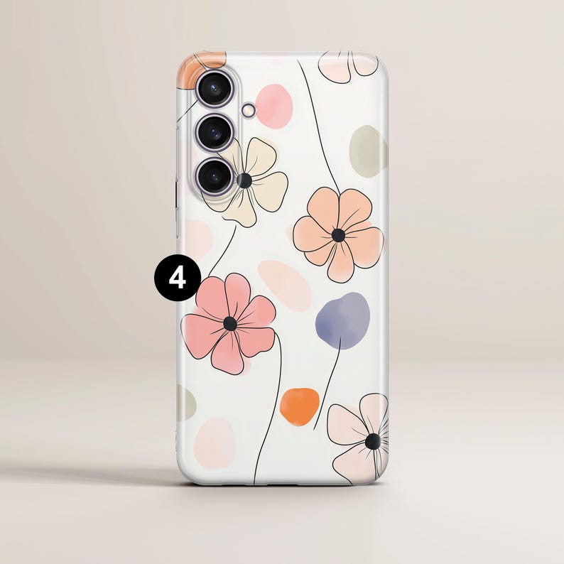 May include: A white phone case featuring a floral design with black outlines. The flowers are in shades of pink, peach, and beige, with colorful abstract shapes. The phone case has a camera module with three lenses.