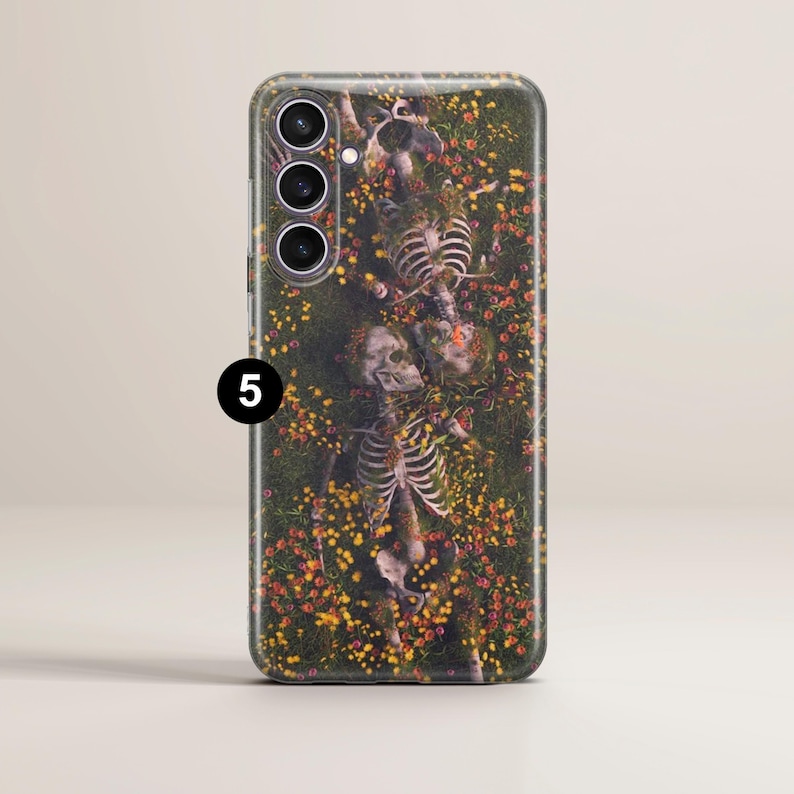 May include: A phone case with a floral design featuring skeletons lying in a field of flowers. The case has a black camera housing with three lenses.