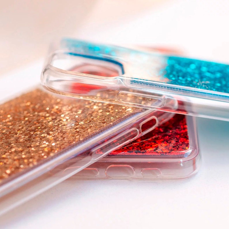 May include: Three clear phone cases with glitter inside. The top case has blue glitter, the middle case has red glitter, and the bottom case has gold glitter.
