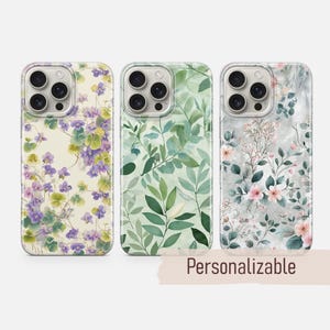 May include: Three phone cases with floral designs. The first case features purple and yellow flowers on a cream background. The second case has green leaves. The third case has pink flowers and gray marble. The word "Personalizable" is on the bottom.